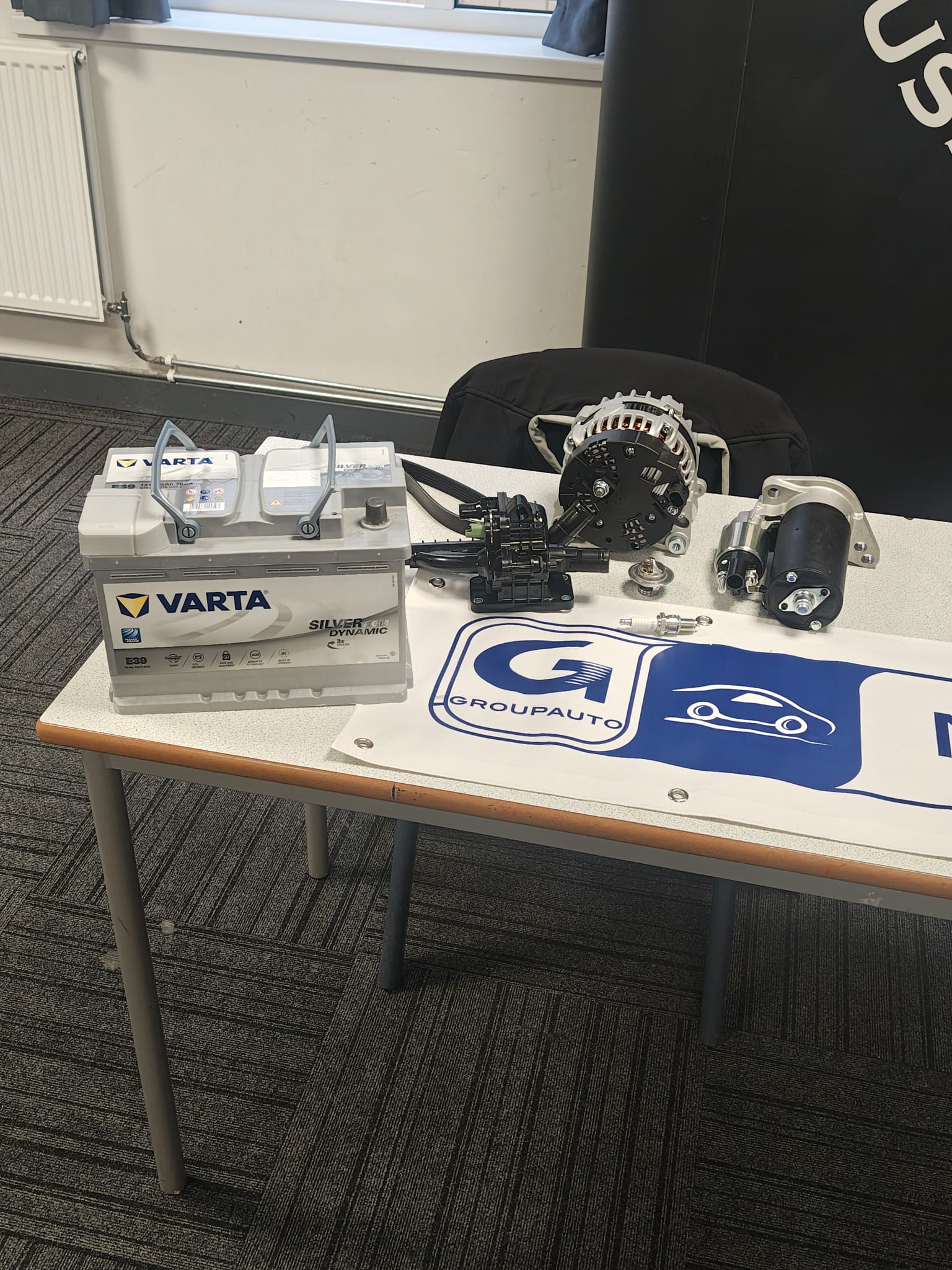 Millfield Auto Parts display table with Varta battery, alternator, starter motor and ignition parts.
